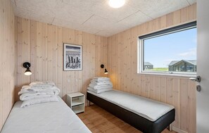 Een kamer met twee bedden, een raam en een foto aan de muur.