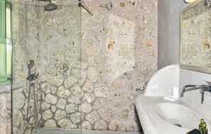 A bathroom with a stone wall, a shower, and a sink. - Luxurious home in Lefkada with private swimming pool, can be inside or outside (Lefkada)