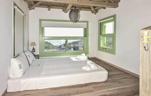 A room with a bed, a window with a view of a forest, and a hanging light fixture. - Luxurious home in Lefkada with private swimming pool, can be inside or outside (Lefkada)