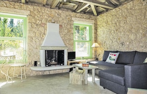 A rustic interior with a stone wall, a fireplace, a sofa, and a table. - Luxurious home in Lefkada with private swimming pool, can be inside or outside (Lefkada)