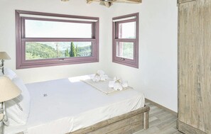 A bedroom with a bed, two windows, a lamp, and a view of greenery. - Amazing home in Lefkada with private swimming pool, can be inside or outside (Lefkada)