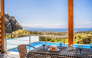 A terrace with a table set for dining, overlooking a pool and a scenic view of the sea and mountains. - Stunning home in Rethymno Crete (Rethymno Crete)