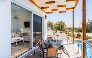 A covered outdoor seating area with a checkered tablecloth, wicker chairs, and a poolside view. - Awesome home in Rethymno Crete (Rethymno Crete)