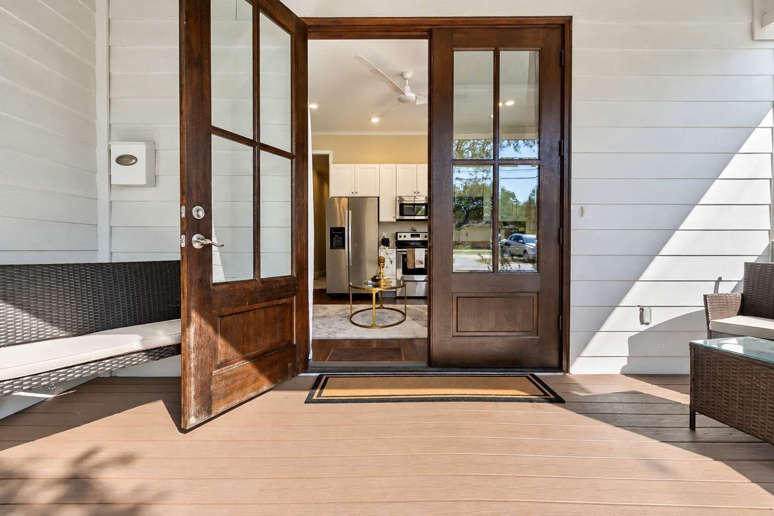 A wooden door leading to a kitchen with white cabinets and a microwave.