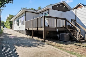 A row of mobile homes with a wooden deck and a staircase leading to the entrance. - Southern Row | Two King Bedrooms | Walk to UA (Tuscaloosa)