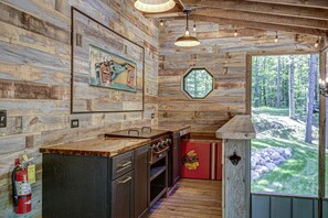 A rustic cabin interior with a wooden interior, a kitchen area, and a view of the forest through a window. - Ridge Top Ranch - Private Northwoods Retreat (Cassian)