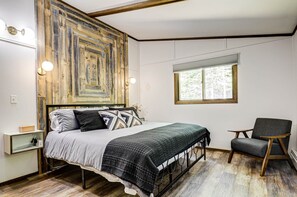 A bedroom with a bed, a chair, a window, and a wall with a geometric wooden design. - Ridge Top Ranch - Private Northwoods Retreat (Cassian)