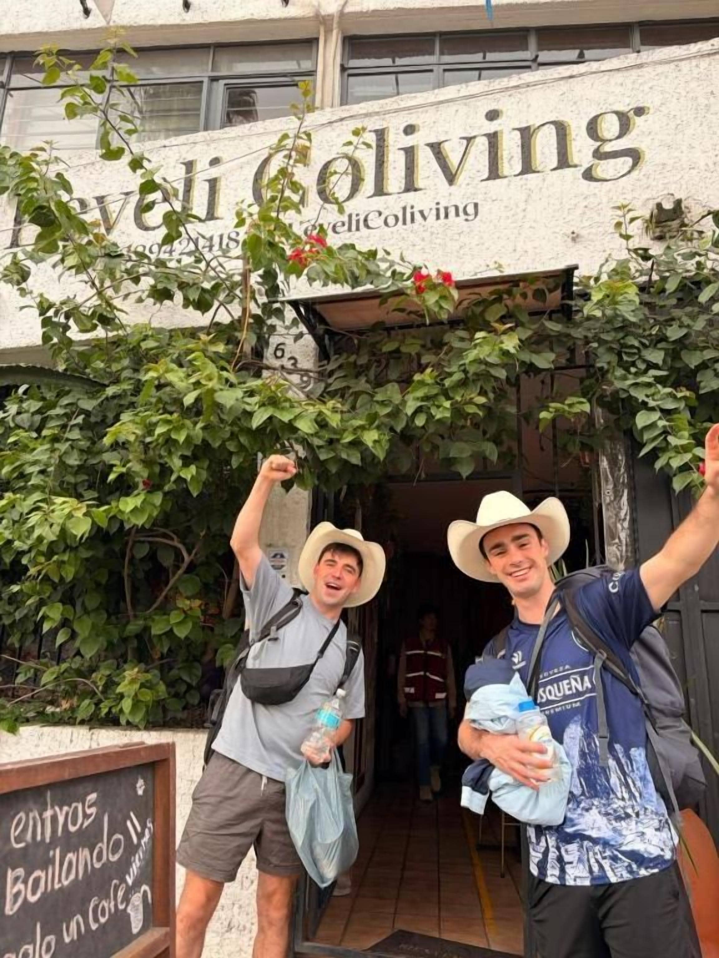 Two individuals standing in front of a building with a sign that reads 'Coliving.'
