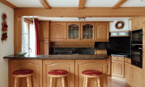 Eine Küche mit Holzschränken, einer Marmorarbeitsplatte und einem schwarzen Backofen.