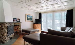 A living room with a stone fireplace, a television, a sofa, and a window with curtains. - A WONDERFUL BALANCE OF TRANQUILITY, CONVENIENCE & SPECTACULAR MOUNTAIN SCENERY (Zermatt)