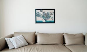Ein beiges Sofa mit einem einzelnen weißen Kissen vor einer schlichten Wand.