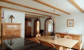 A dining area with a wooden table and chairs, a chandelier, and a brick archway leading to another room. - A WONDERFUL BALANCE OF TRANQUILITY, CONVENIENCE & SPECTACULAR MOUNTAIN SCENERY (Zermatt)