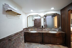Un baño con dos lavamanos, un espejo grande y un perchero para toallas.