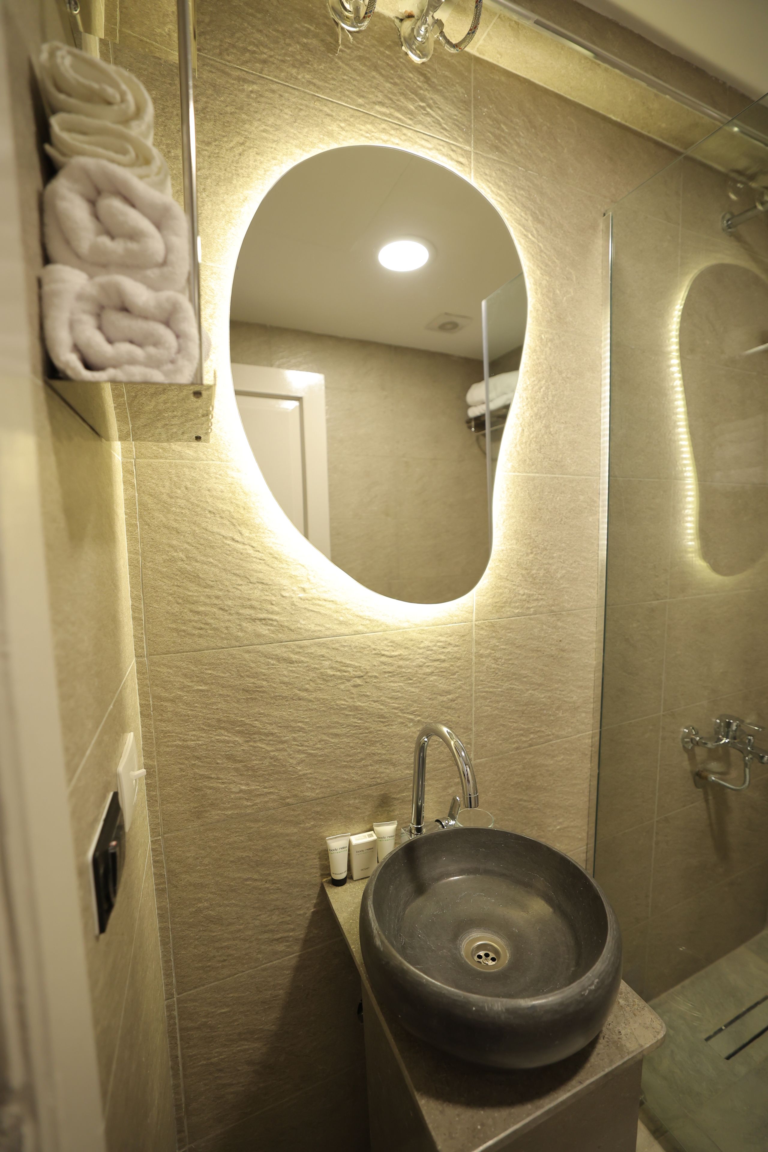 Un bagno con uno specchio tondo, un lavandino e un porta asciugamani.