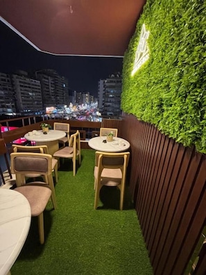 Una terraza en la azotea con un muro verde y mobiliario de madera.