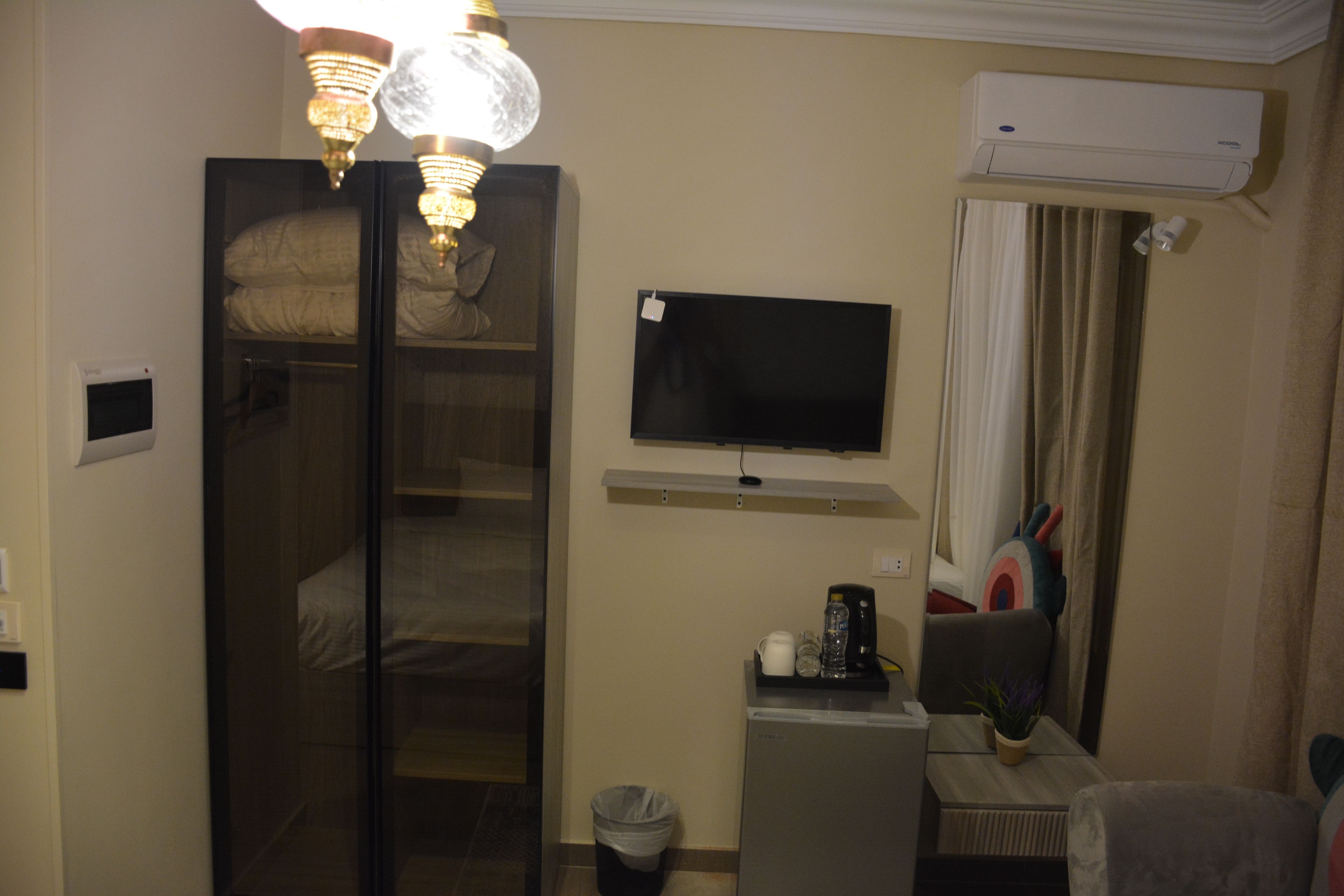 Une chambre d’hôtel équipée d’un lit, d’une télévision, d’un bureau avec une chaise, d’une poubelle et d’un appareil de climatisation.