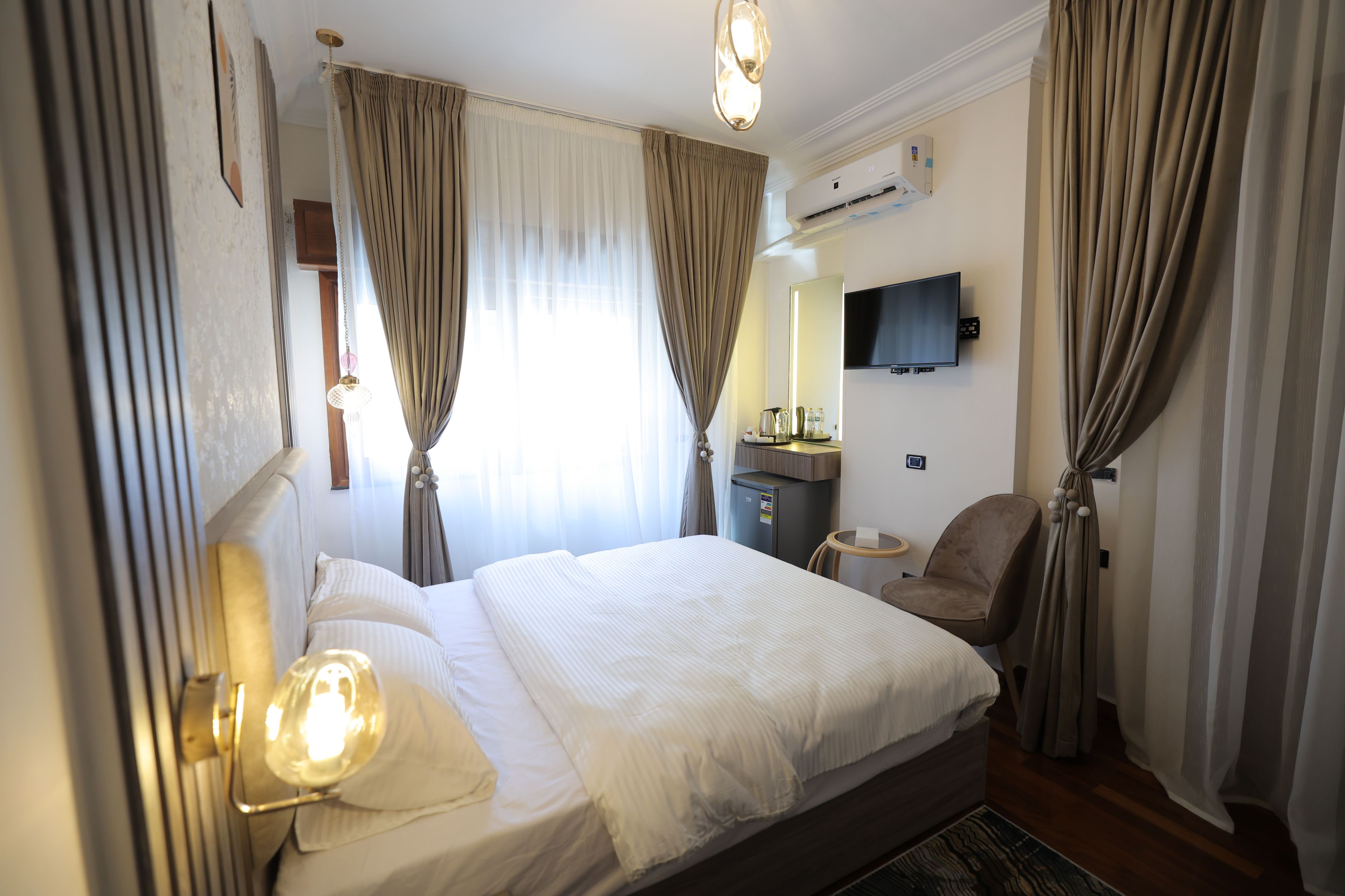Une chambre d’hôtel équipée d’un lit, d’un bureau, d’une chaise, d’une télévision et d’un appareil de climatisation.