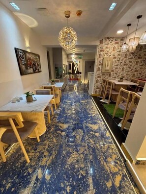 Un pasillo de hotel con piso de mármol azul, muebles de madera e iluminación colgante.