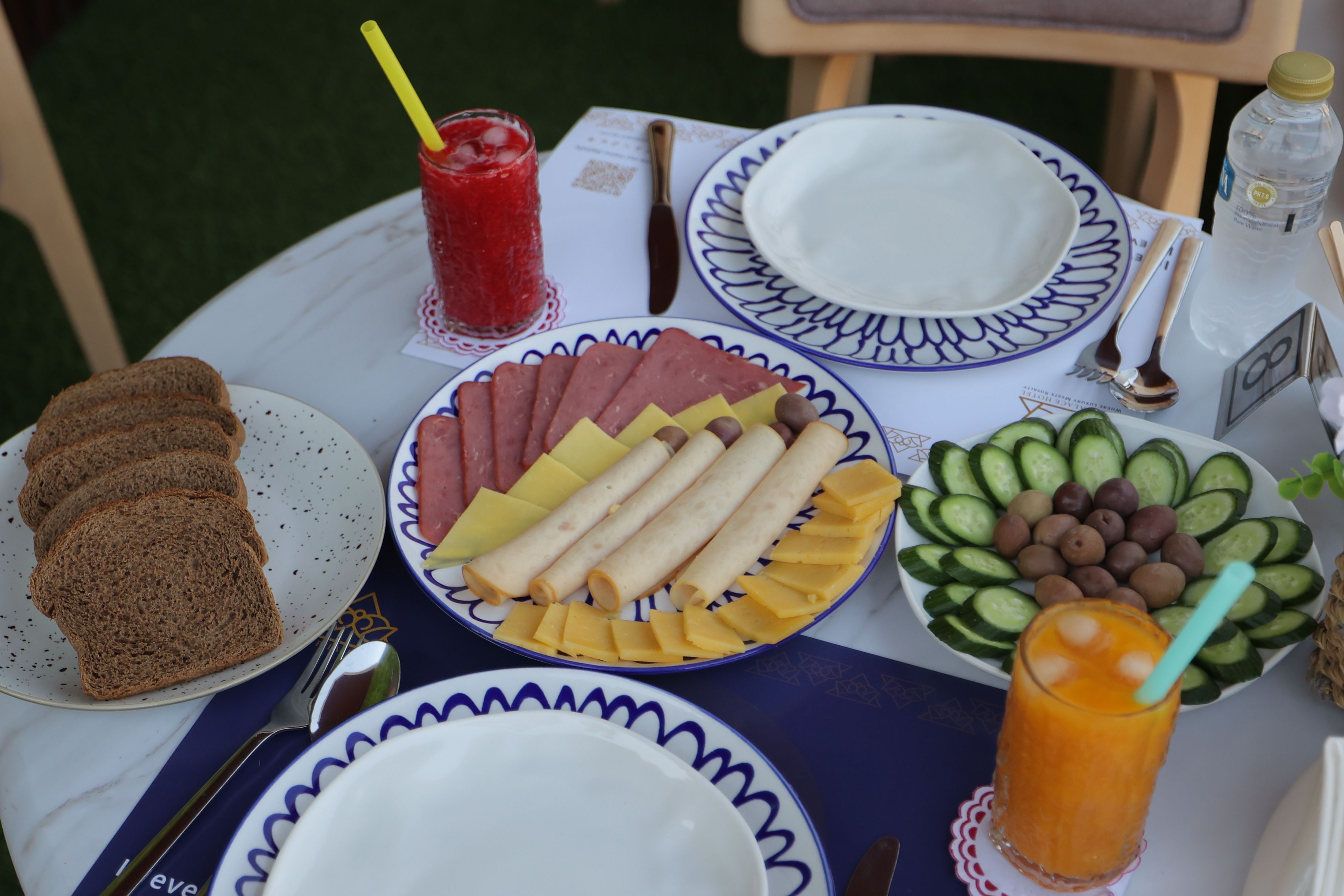 Una mesa dispuesta con platos de comida, un vaso de jugo y una botella de agua.