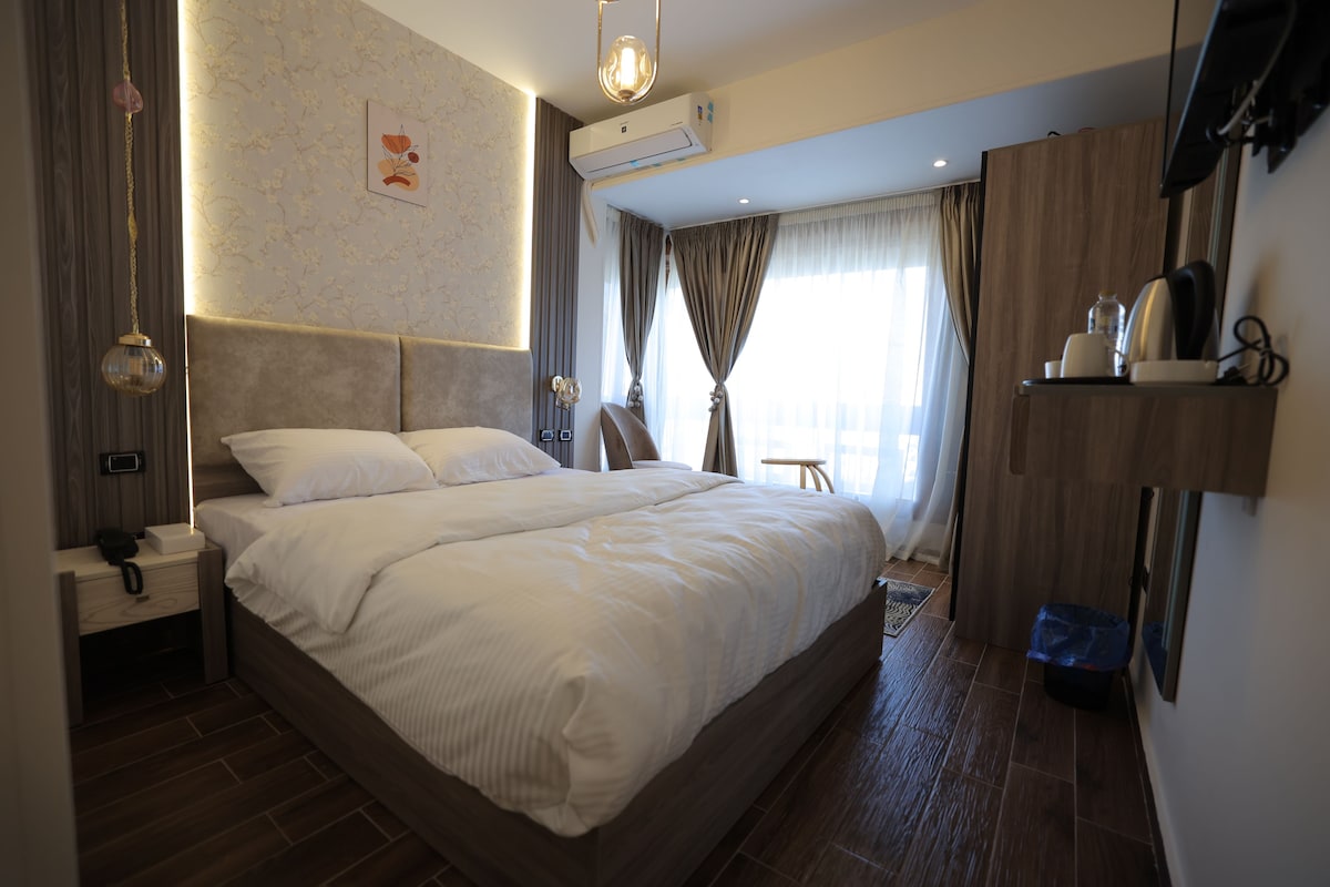 Un dormitorio moderno con una cama grande, mesitas de noche, un equipo de aire acondicionado y un televisor en la pared.
