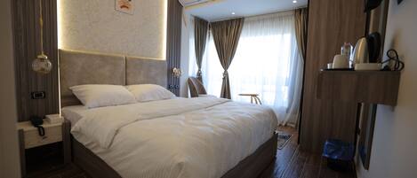 A modern bedroom with a large bed, bedside tables, an air conditioning unit, and a television on the wall.