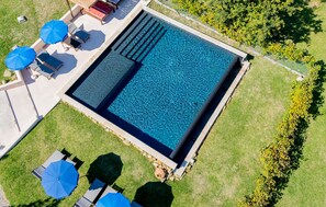 An aerial view of a rectangular swimming pool with a clear blue surface, surrounded by a grassy area with lounge chairs and umbrellas. - Stunning home in Serra San Quirico with outdoor swimming pool (Serra San Quirico)