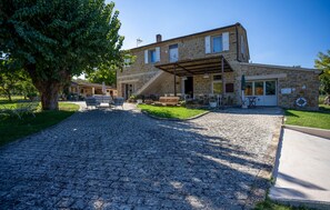 A stone building with a covered patio area, outdoor seating, and a cobblestone driveway. - Stunning home in Serra San Quirico with outdoor swimming pool (Serra San Quirico)