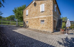 A stone building with a cobblestone driveway, a gate, and a staircase leading to a covered area with outdoor furniture. - Amazing home in Serra San Quirico with outdoor swimming pool (Serra San Quirico)