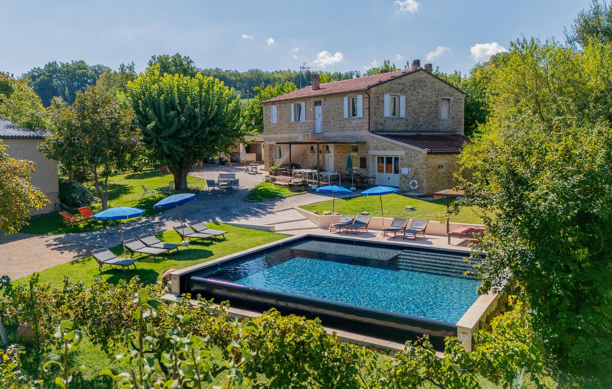 A stone house with a swimming pool, outdoor seating, and a well-maintained garden.