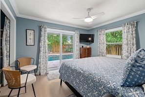 Une chambre à coucher avec un lit, une chaise, un téléviseur et une fenêtre avec des rideaux.
