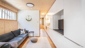 Ein modernes Wohnzimmer mit einem grauen Sofa, einem kleinen runden Tisch und einem dekorativen Kranz an der Wand.