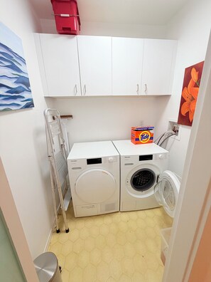 Une buanderie équipée de deux machines à laver, d’un radiateur et d’une boîte de lessive Tide.