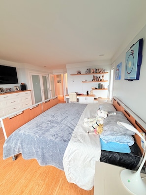 A bedroom with a bed, bedside table, and a desk with a chair. There are shelves with books and decorative items. - Superb 2 BR Oak Bay Condo on Willows Beach (Victoria)