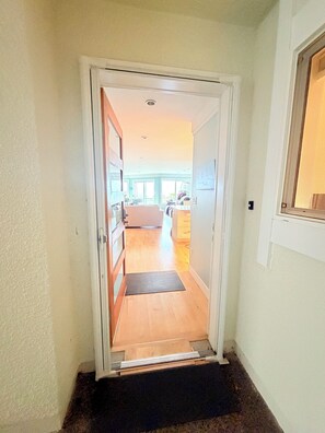 A hallway leading to a living area with a door, a doormat, and a window on the right. - Superb 2 BR Oak Bay Condo on Willows Beach (Victoria)