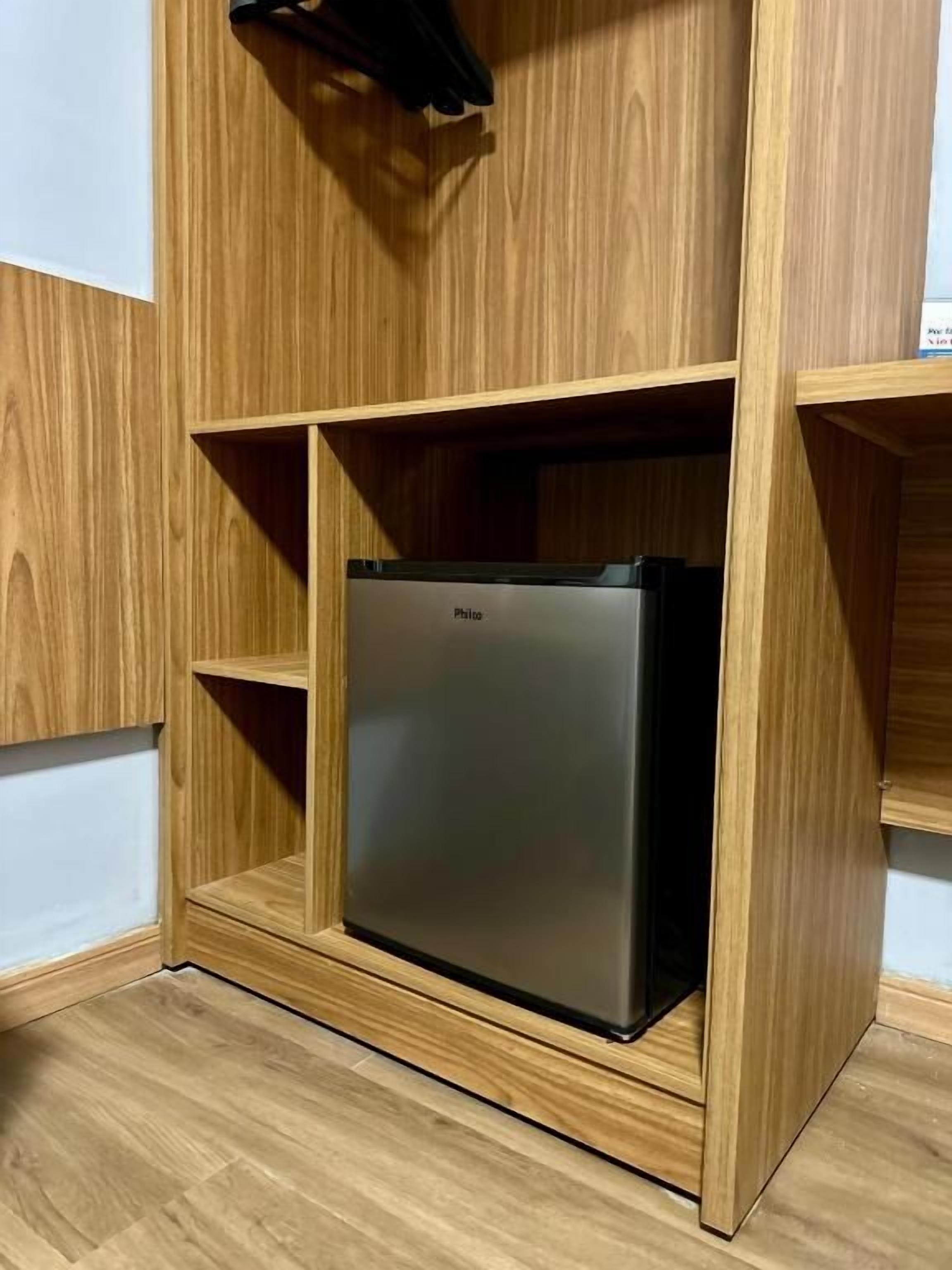 Cocina moderna y compacta con refrigerador de acero inoxidable integrado y muebles de madera.