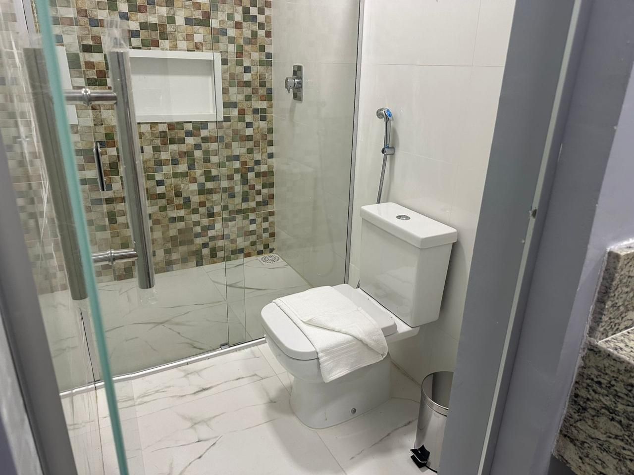Ein Badezimmer mit Dusche, Toilette und Fliesen.