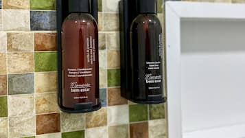 Dos botellas de champú y acondicionador sobre una pared de baldosas.