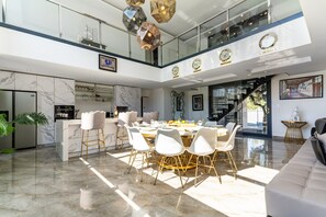 A spacious dining area with a high ceiling, modern chandeliers, and a view of the sky. - Villa Les Vagues • Pool, hot tub & beach 500 m away (Agde)