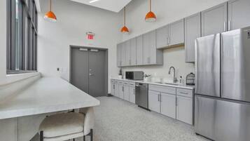 A modern kitchen with stainless steel appliances, grey cabinets, and pendant lighting.
