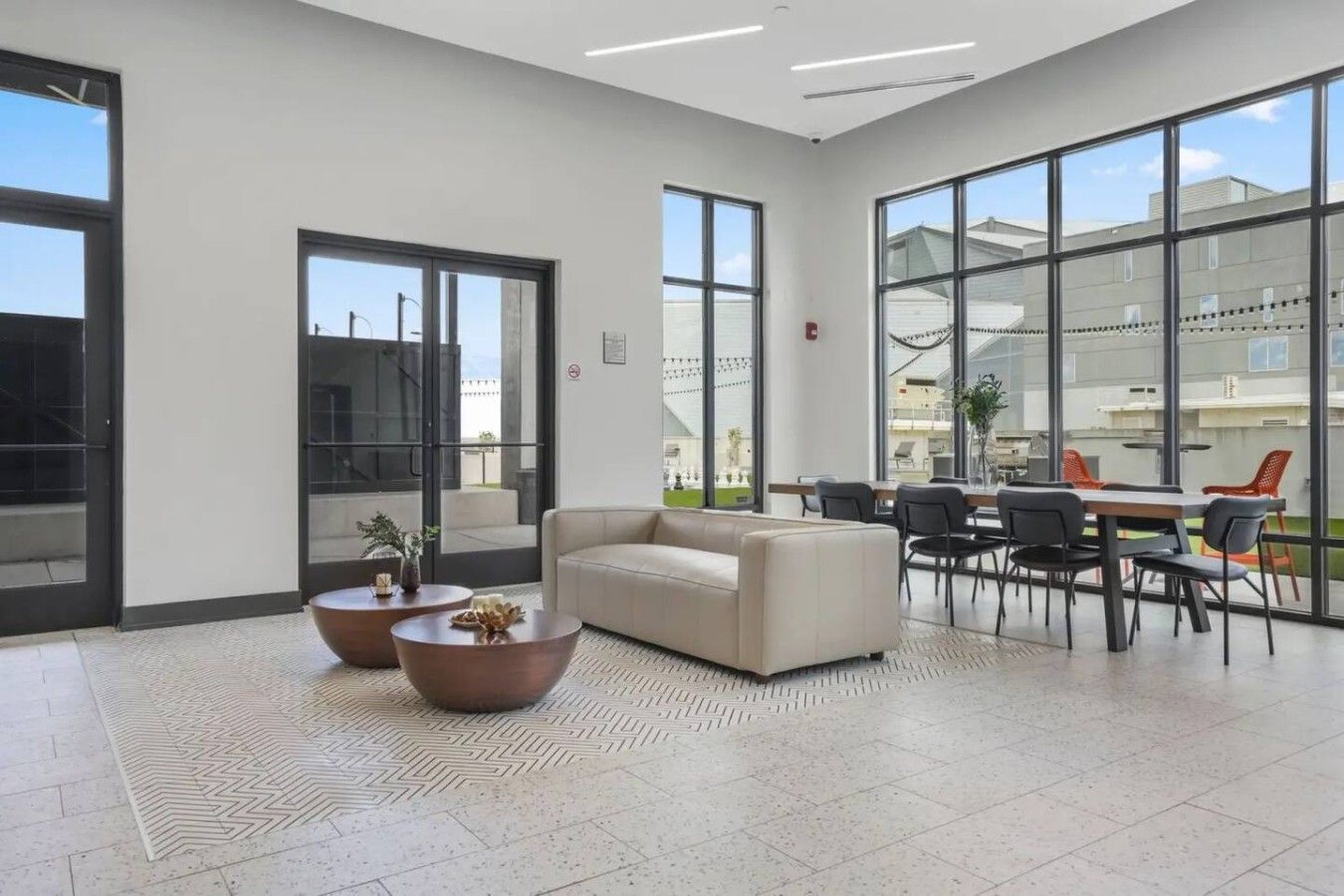 A spacious lobby with a sofa, coffee tables, and a dining area with chairs.