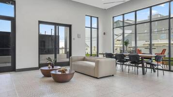 A spacious lobby with a sofa, coffee tables, and a dining area with chairs.