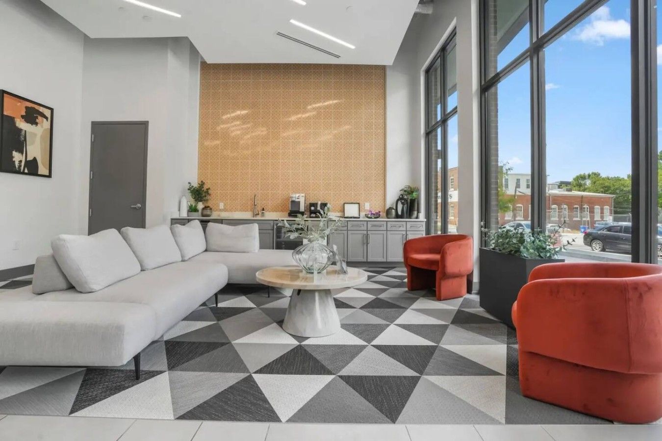 A modern interior with a sectional sofa, a round coffee table, and red chairs.