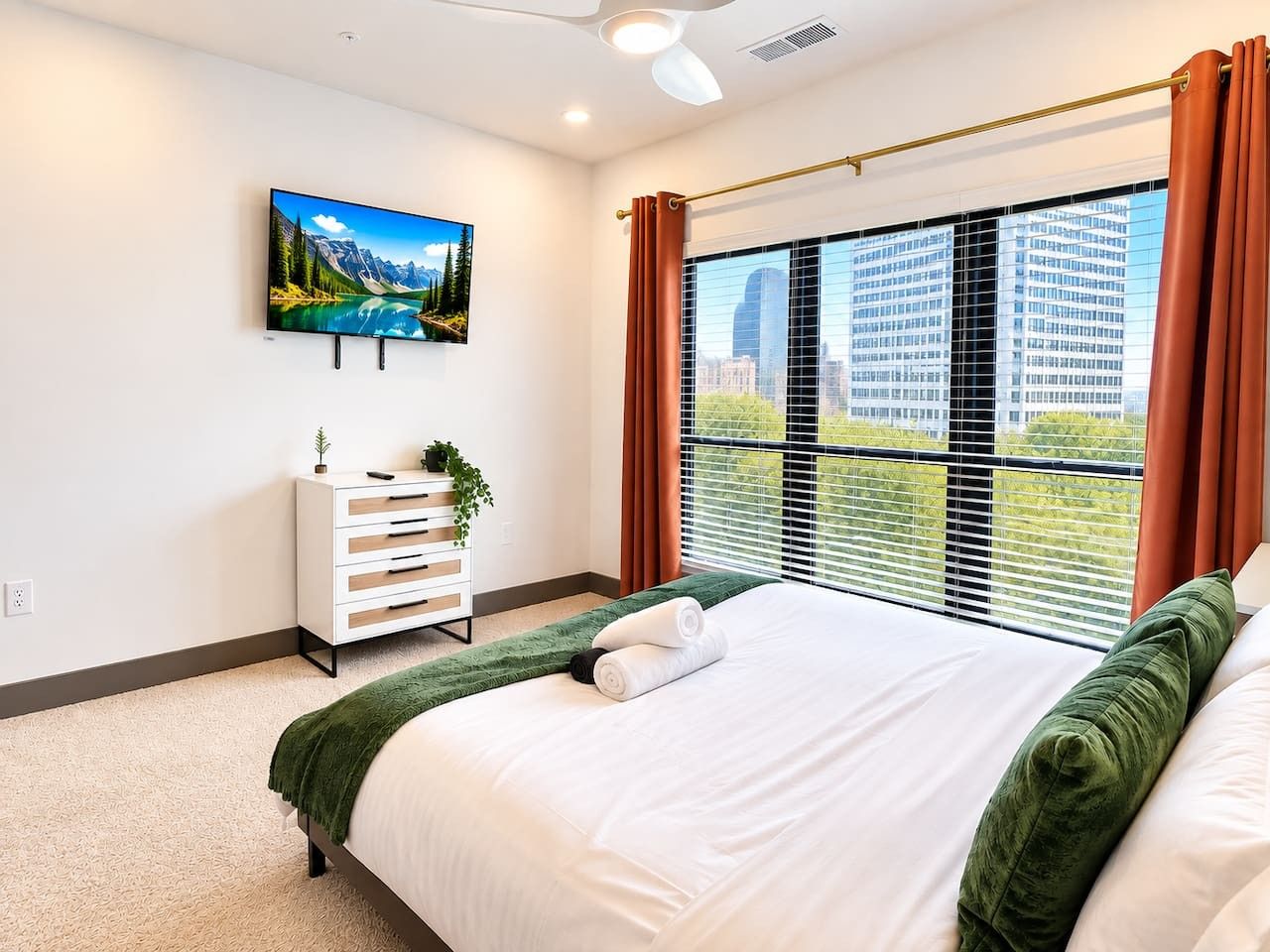 A hotel room with a bed, a dresser, a painting, and a window with curtains.