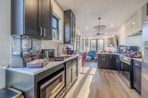 A modern kitchen with dark cabinetry, a built-in oven, a microwave, and a blender. - NEW Cowgirl Brownstone near UT - 3 king suites, rooftop deck w Hottub (Knoxville)