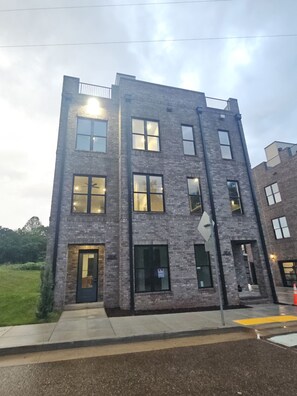 A multi-story building with a brick facade, large windows, and a visible door. - NEW Speakeasy Brownstone near UT - 3 king suites, rooftop deck w Hottub (Knoxville)