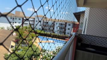 Una cerca de malla con vista a una piscina y edificios al fondo.