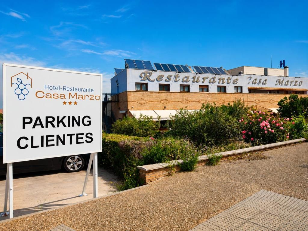 Een hotel met een bord waarop 'Hotel-Restaurante Casa Marzo' staat en een bord met 'PARKING CLIENTES'.