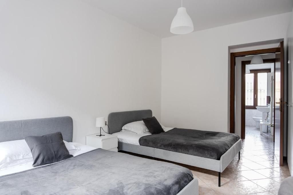 Une chambre moderne avec deux lits, une table de chevet et une salle de bain visible à travers une porte ouverte.