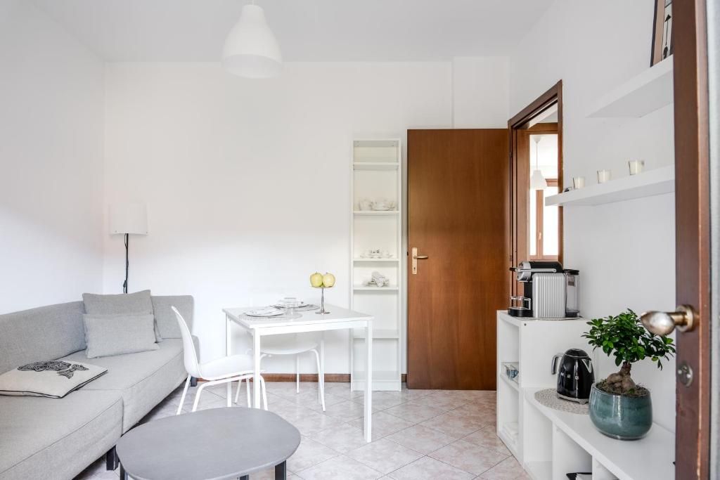 A compact living space with a sofa, a dining table, chairs, a coffee machine, and a potted plant.