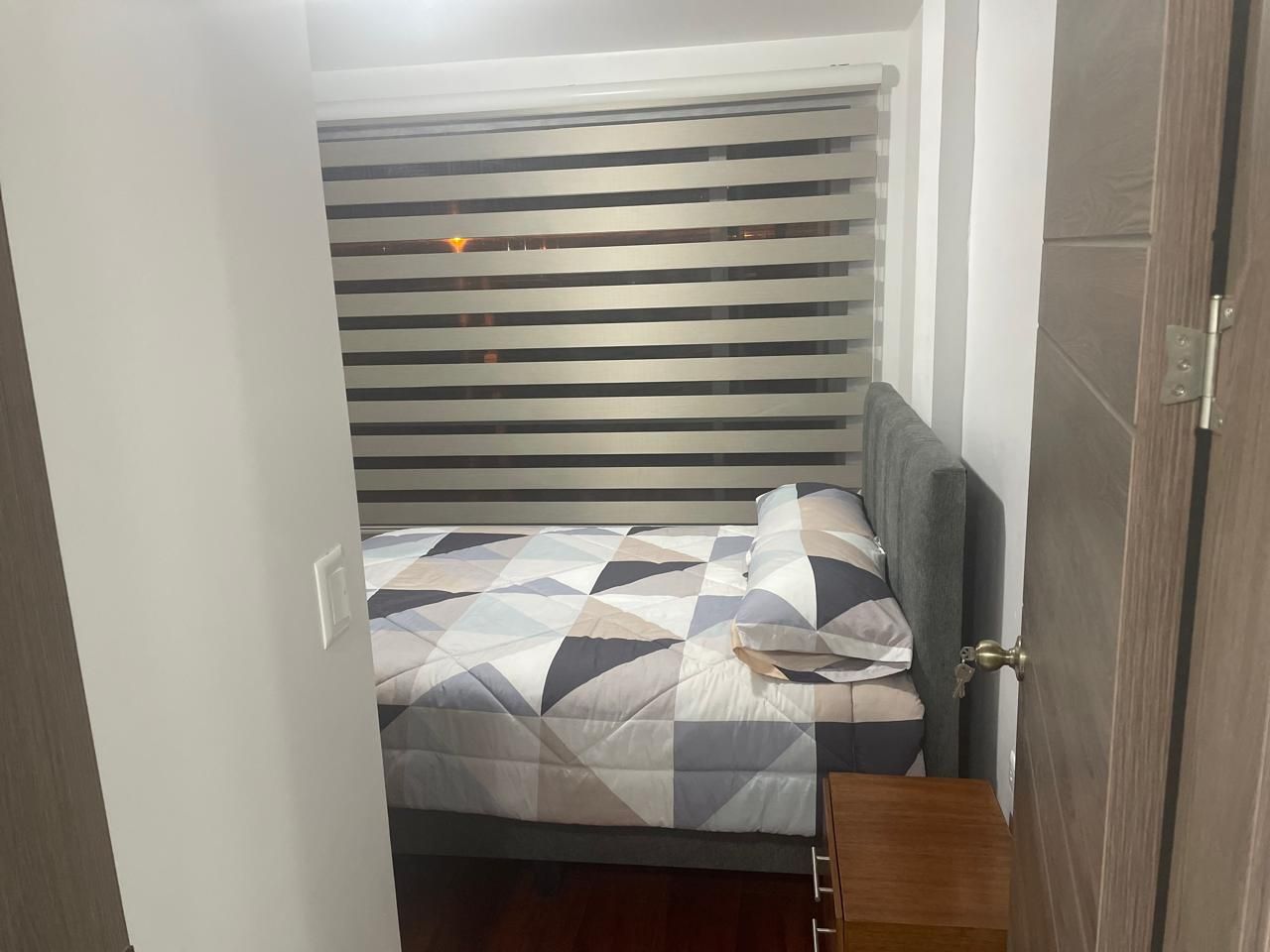 A compact bedroom with a bed, a bedside table, and a door.